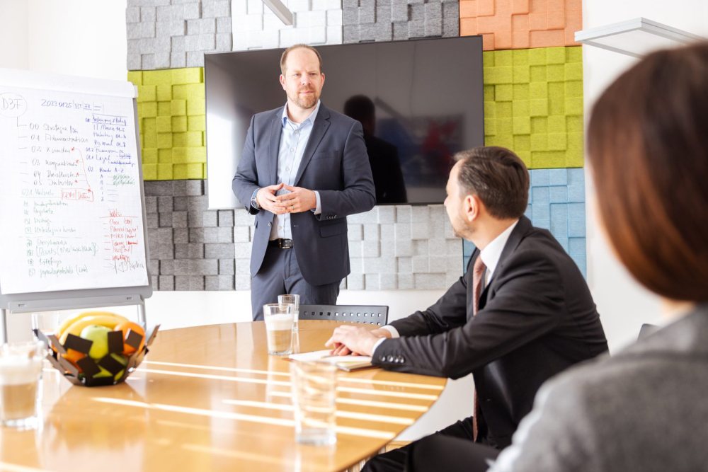 SPENDEX Experte präsentiert am Flipchart vor Kunden im Besprechungsraum